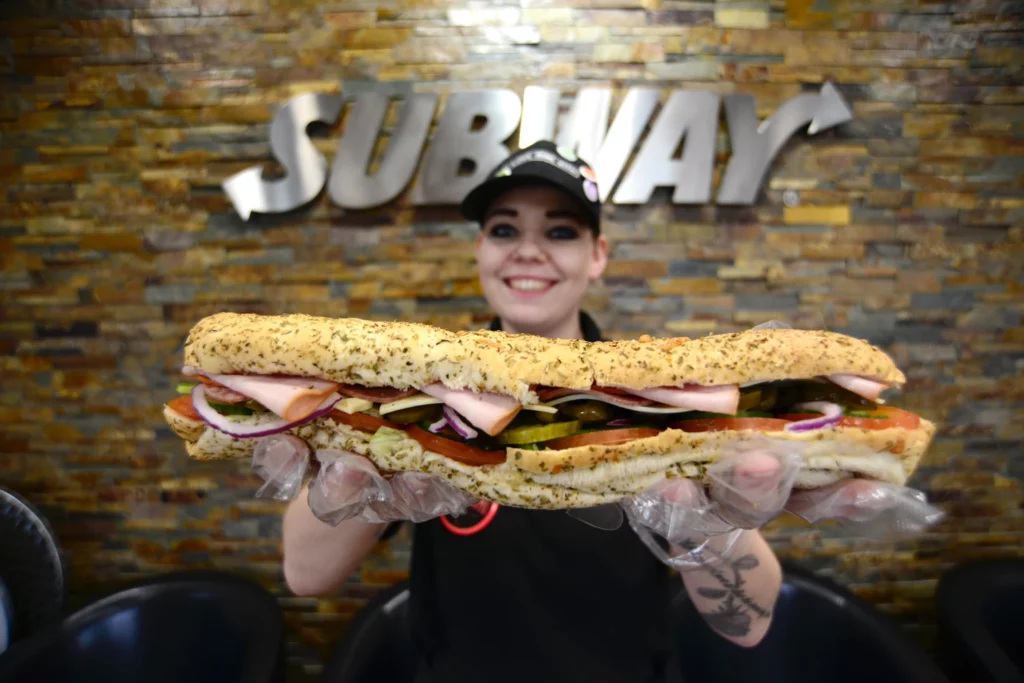 A Subway staff member holding a footlong sandwich.Scott Bairstow / Alamy Stock